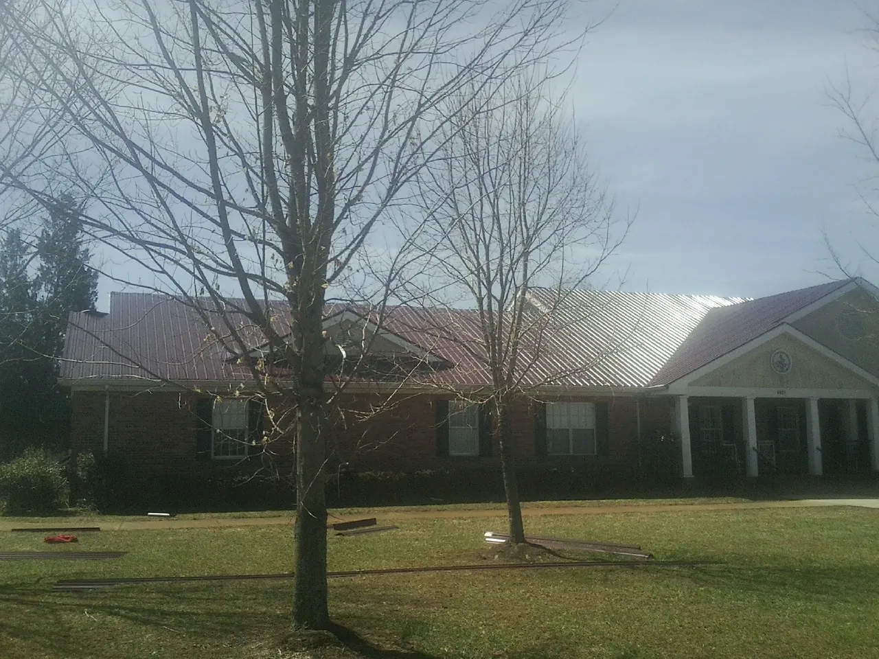 Red metal roof on a brick building seen from the front lawn in Stewartville