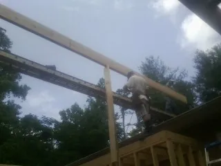 Carpenter setting a ridge beam over a new addition frame — Ice Dam Removal by Roofing Brothers in Stewartville