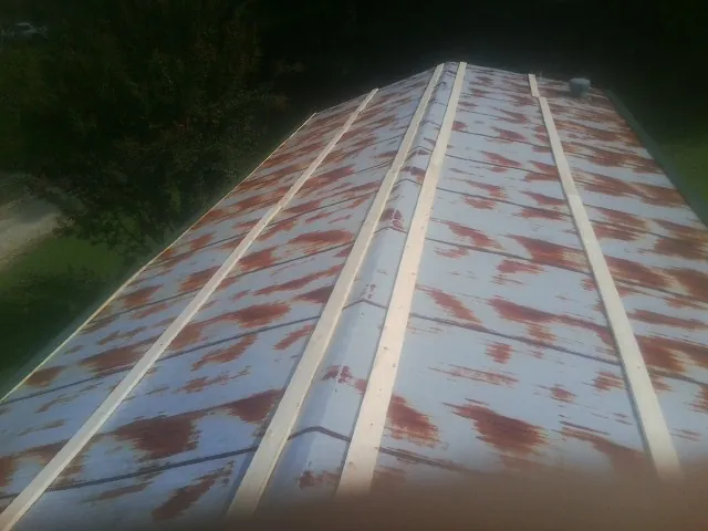 Rusted metal roof panels with new wood purlins before replacement — Storm Damage Roof Repair in Stewartville by Roofing Brothers