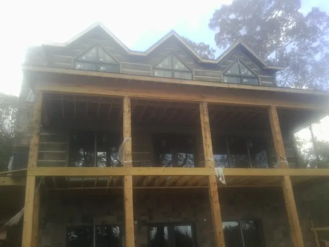 Dormers and porch framing on a large log home under construction — Roof Coating work by our crew in Stewartville
