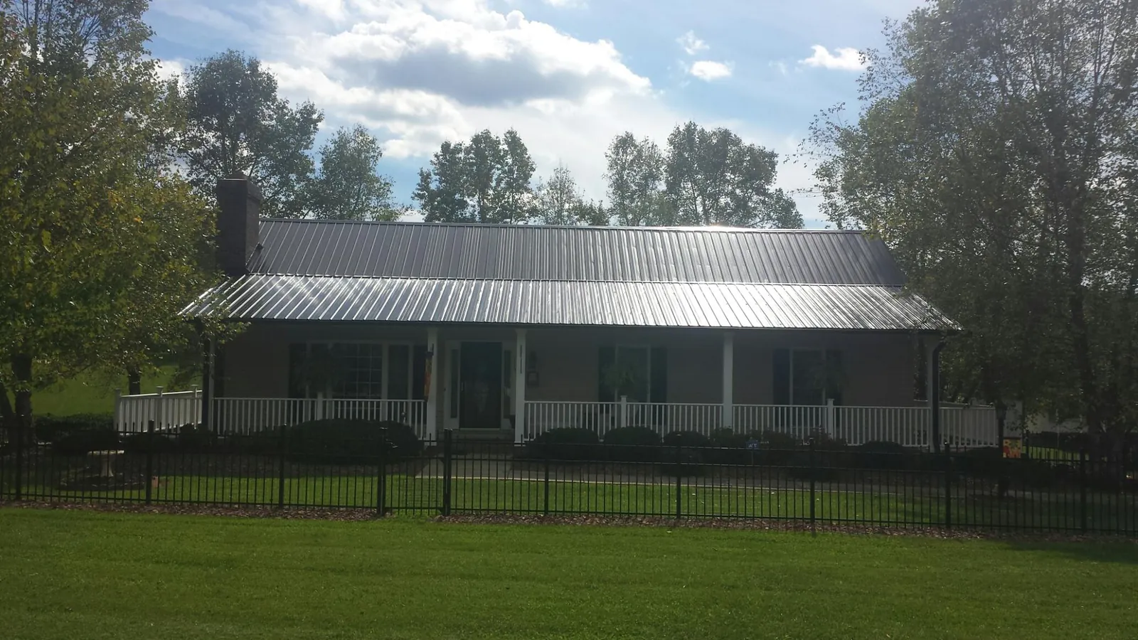 Gray metal roof on a brick ranch with a full width front porch — Gutter Guard Installation work by our crew in Stewartville