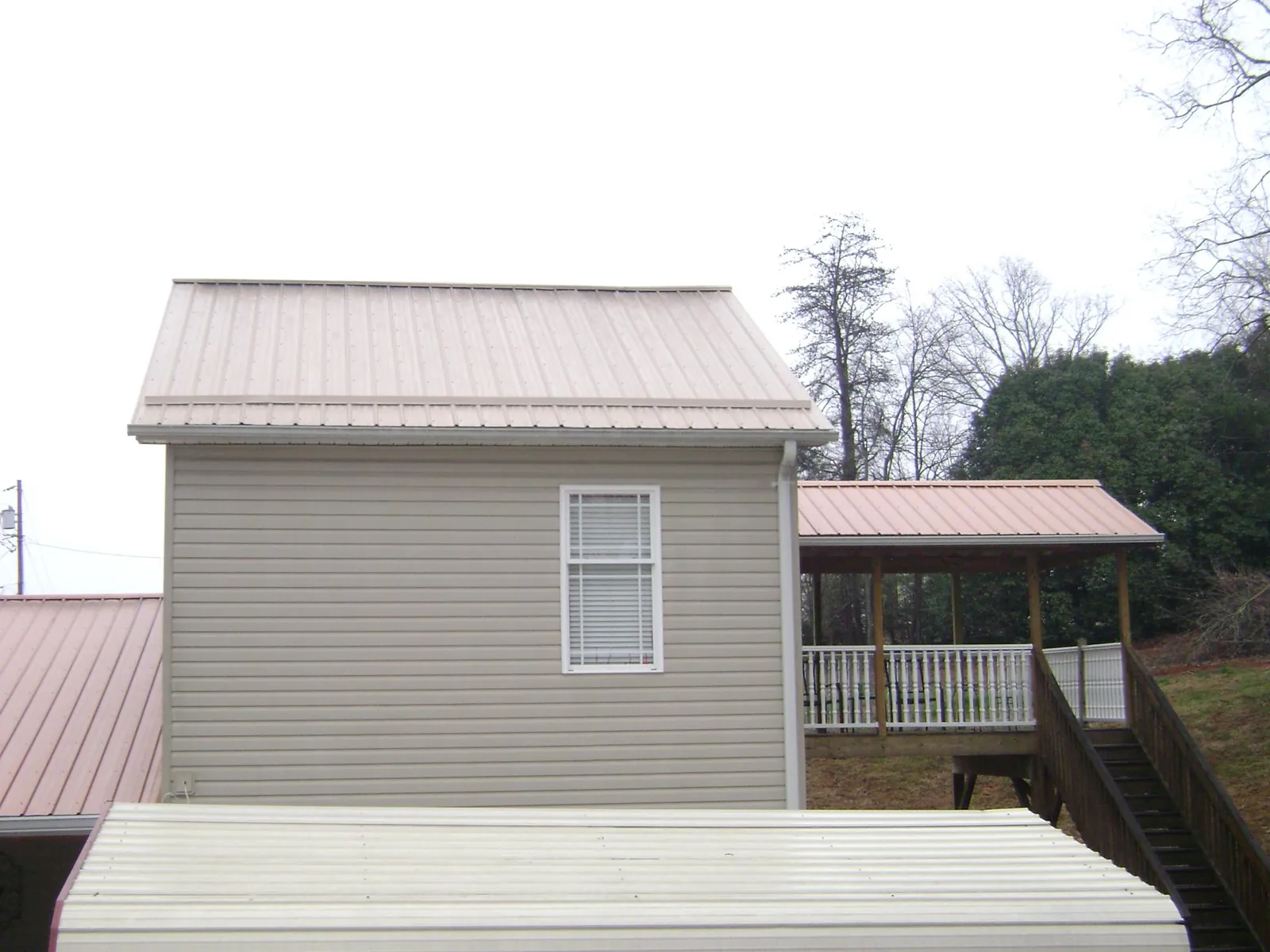 Tan metal roofs on a two story addition and attached porch, from a Roof Replacement job in Stewartville