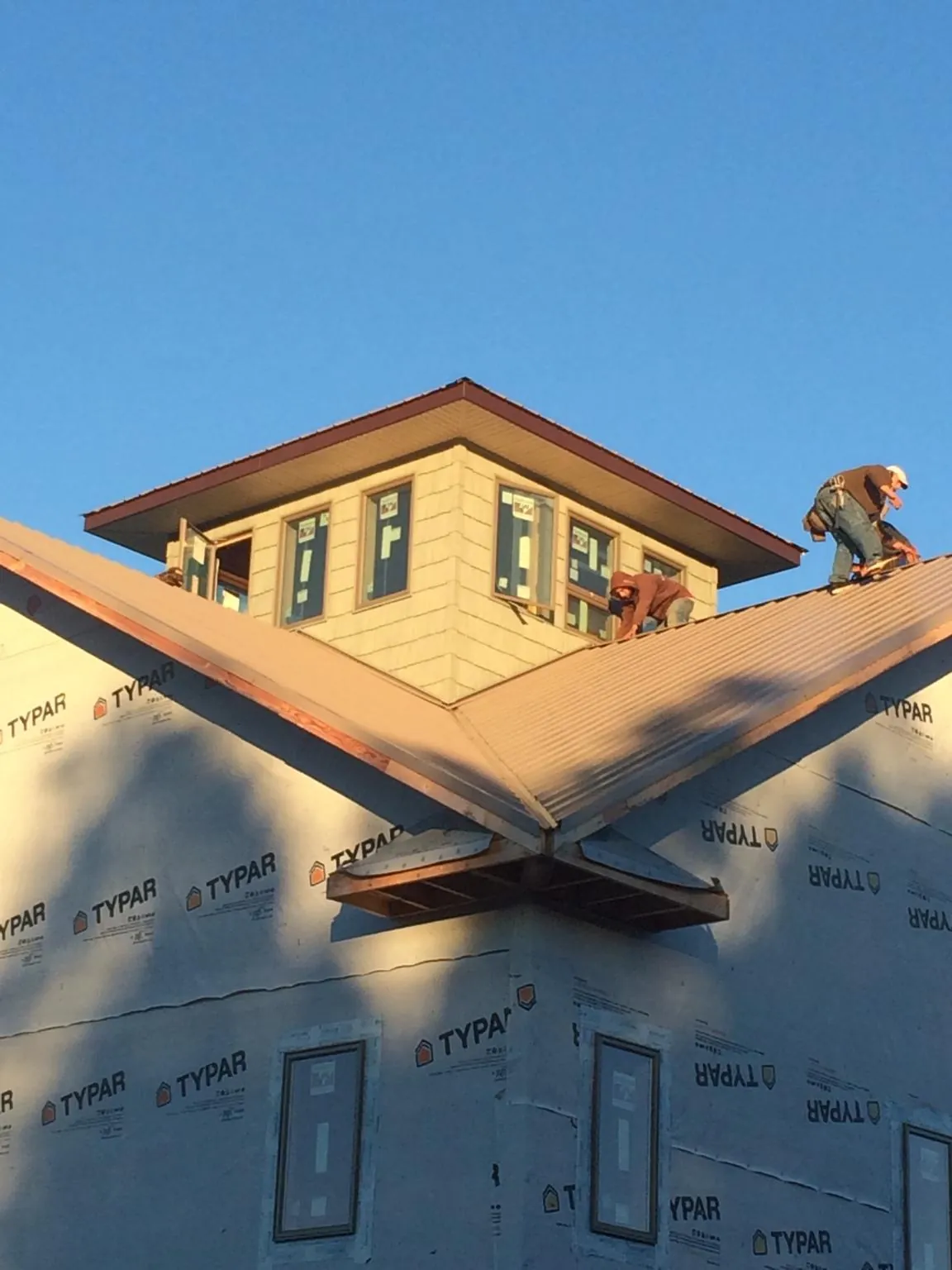 Roofers working around a rooftop cupola on a new metal roof at sunset — Roof Waterproofing in Stewartville by Roofing Brothers